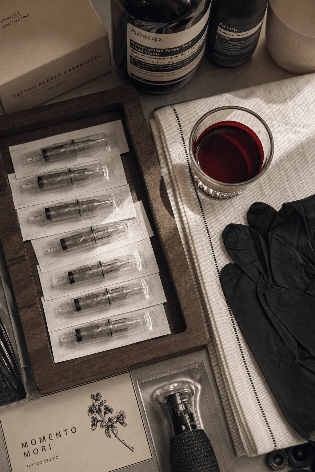 Top-down photograph of professional lip blushing equipment — sterile single-use needle cartridges, pigment, gloves.